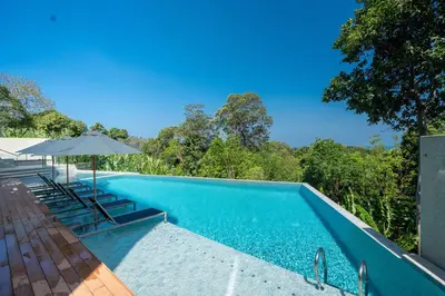 an empty swimming pool with an umbrella and chairs at Sapphire Bay Luxury Condominiums Patong, 811 in Patong Beach