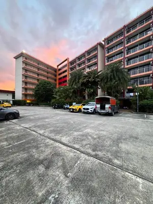 a parking lot with cars parked in front of a large building at Maikhao Beach Condominium in Mai Khao Beach
