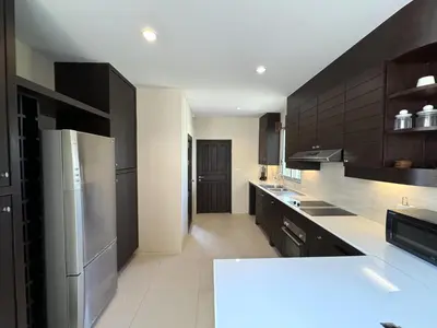 a large kitchen with black cabinets and stainless steel appliances at Nai Thon villa with pool, garden, rooftop terrace in Nai Thon Beach