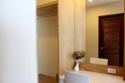 a room with a table with two chairs and a vase with flowers at The Little Nest Phuket in Phuket Town