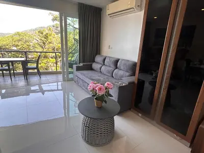 a living room with a couch and a table with flowers at Karon Butterfly Condominium Brandnew, spacious 65m2 full seaview apartment, large pool, 300m from Karon beach in Karon Beach