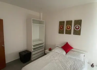 a bedroom with a white bed with a red pillow at Pool Villa in Thalang in Ban Na Nai