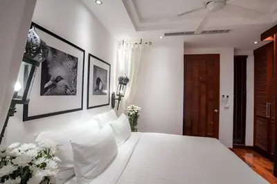 a white bedroom with a large white bed with white pillows at Villa in the Park, Surin Beach, Phuket in Surin Beach