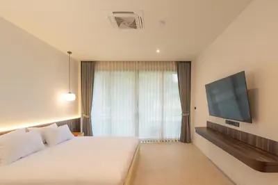 a bedroom with a white bed and a flat screen tv at The Pinnacle Katanoi in Kata Beach