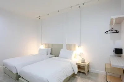 two beds in a room with white walls at Lfour phuket in Phuket Town