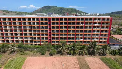 an orange building with palm trees in front of it at Уютная квартира рядом с пляжем Май Као in Ban Mai Salae