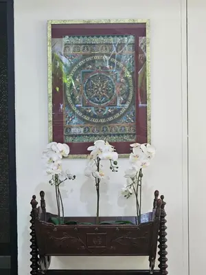 a vase with white flowers in front of a picture at Eden Villas Kamala in Kamala Beach