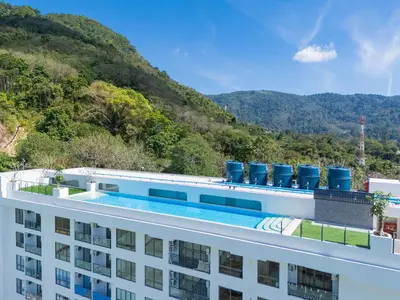 a hotel with a swimming pool and mountains in the background at Japanese-Style Condo close Kamala Beach in Kamala Beach