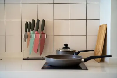 a pan on a stove with knives on a wall at Japanese-Style Condo close Kamala Beach in Kamala Beach