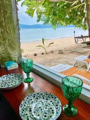 a wooden table with plates and glasses on a beach at Beach Loft in Ko Thanan
