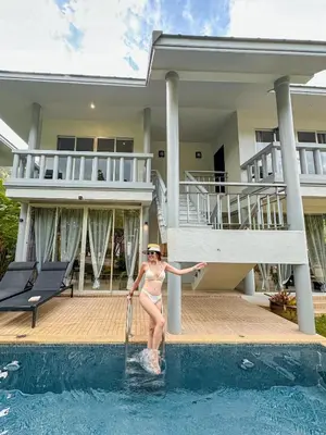 a woman in a bikini standing in a pool in front of a house at Casa Sakhu Beach Villa Phuket in Nai Yang Beach