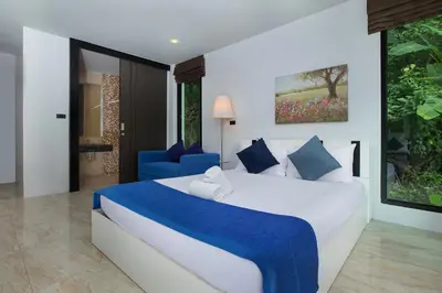 a bedroom with a large bed and a blue chair at 4BR Villa B5 with Pool, Vibrant Life at Kata Beach - UTK5 in Kata Beach