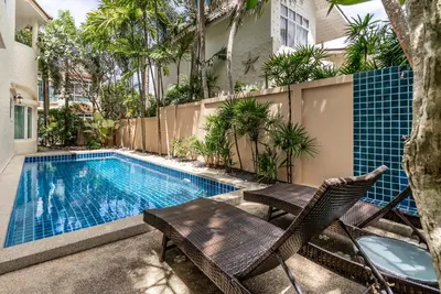 a swimming pool with chairs and a table next to a building at Med Village by Villacarte in Nai Harn Beach