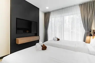 two beds in a hotel room with a television at Med Village by Villacarte in Nai Harn Beach