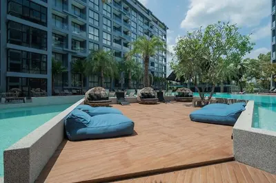 a swimming pool with blue pillows on a wooden deck at Tropical Pool View 2 BR Apartment CTG B207-8 in Tropics Kamala Residence in Kamala Beach