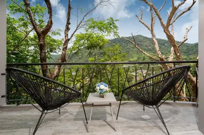 a balcony with two chairs and a vase of flowers at Embrace Nature, Comfort & Beach Proximity - Natural Park B24 Suite, Kamala in Kamala Beach