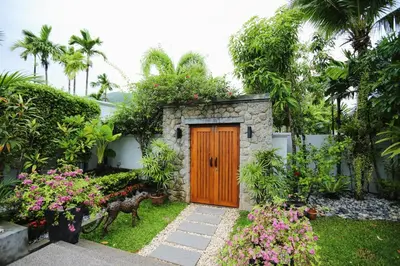 a wooden door in a garden with flowers and plants at 06 - Luxurious & Lavish Getaway in Surin Beach in Surin Beach