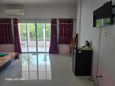 a room with a bed and a television and curtains at NW House in Ao Nang Beach