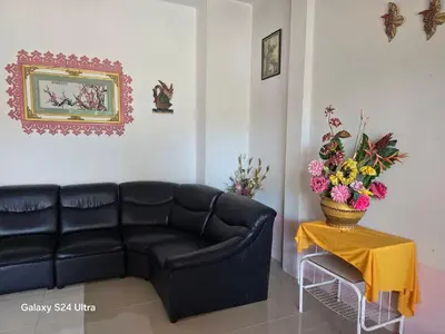 a living room with a black couch and a table with flowers at NW House in Ao Nang Beach