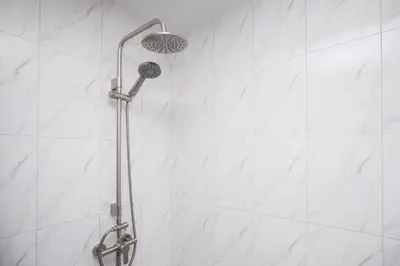 a shower in a bathroom with white tiles at Baan Chom View Residences in Kamala Beach