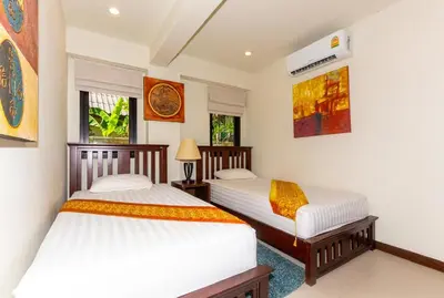 two twin beds in a room with two windows at Naiharn beach sands Apartment in Nai Harn Beach