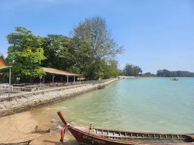 a boat sitting on the shore of a body of water at Zen House Mono in Ban Na Bon