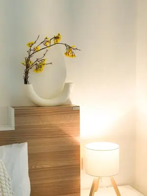 a white vase with yellow flowers on top of a bed at Place Hotel in Kata Beach