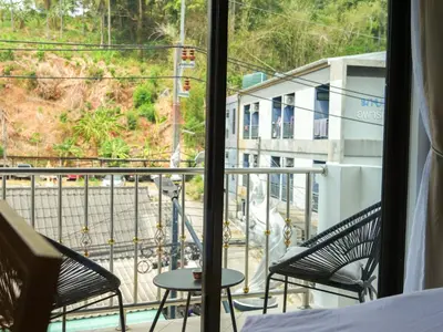 a view of a balcony with two chairs and a table at Place Hotel in Kata Beach