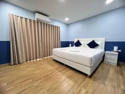 a bedroom with a large white bed and blue walls at Kata walk&wave hostel in Kata Beach