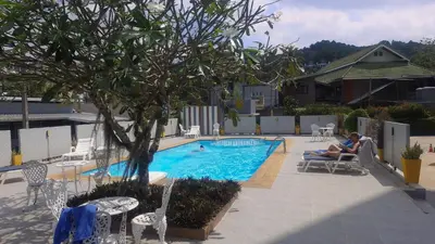 a woman sitting in a chair next to a swimming pool at spacious and modern Apartment in Ao Nang in Ban Khlong Haeng