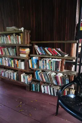 a book shelf filled with books sitting next to a chair at Tropical Hostel in Phi Phi Don