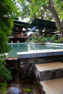 a swimming pool with a waterfall in a garden at Tropical Hostel in Phi Phi Don