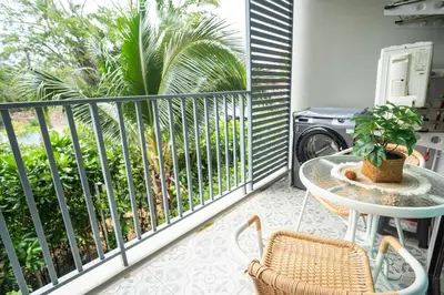 a balcony with a table and chairs and palm trees at Lovely Vlada in Nai Yang Beach