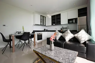a living room with a black leather couch and a kitchen at Elegant Natural Stay at VV Patong Apartment A401 in Patong Beach