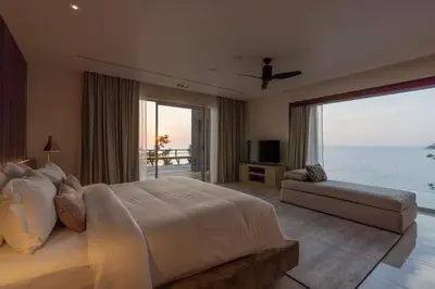 a bedroom with a large bed and a view of the ocean at 33 - The Cove in Laem Singh Beach in Surin Beach