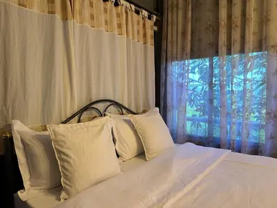 a bedroom with a bed with white pillows and a window at Cashew Garden House in Chalong