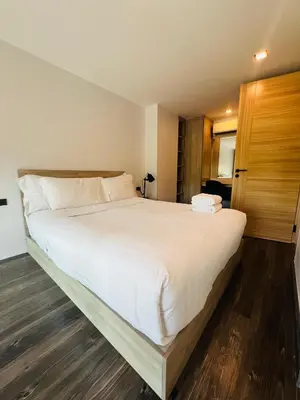 a bedroom with a large white bed with wooden floors at Loft condo in Phuket