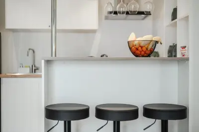 a kitchen with three black stools under a counter at Квартира в The Title Halo 1 in Nai Yang Beach