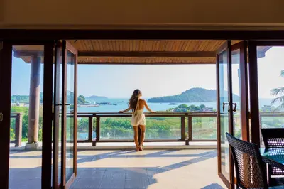 a woman standing on a balcony looking out at the water at Grand View Panwa Luxury Villa in Ban Ao Makham