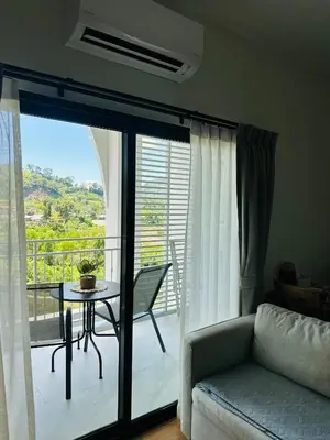 a living room with a couch and a table on a balcony at Title Halo, 2 bedrooms apartment in Nai Yang Beach