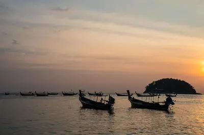 a group of boats in the water at sunset at Sunnyside Kata in Kata Beach