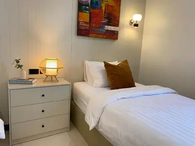 a bedroom with a bed and a night stand with a lamp at Sea Breeze Villa Patong in Patong Beach