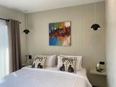 a bedroom with a white bed with a painting on the wall at Sea Breeze Villa Patong in Patong Beach