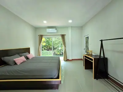 a bedroom with a bed and a desk and a window at Aonang Riverside Home in Ban Khlong Son