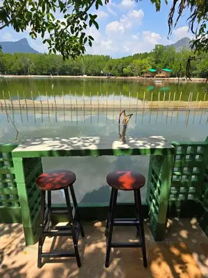 a table with two stools in front of a lake at Aonang Riverside Home in Ban Khlong Son