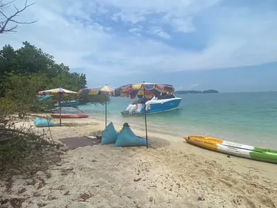 a beach with umbrellas and a boat in the water at Naturist Beach Camping Private Beach Phuket in Ko Lone