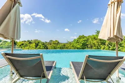 two chairs and umbrellas next to a swimming pool at Bluepoint by Villacarte in Patong Beach