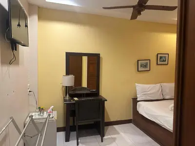 a bedroom with a bed and a desk with a mirror at Taj Palace Patong Beach in Patong Beach