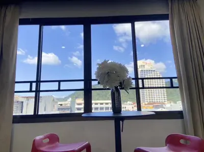 a table with a vase of flowers in a window at Sumer guesthouses in Patong Beach