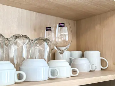 a shelf filled with white cups and wine glasses at New 1BDR Fantasea Kamala beach in Kamala Beach